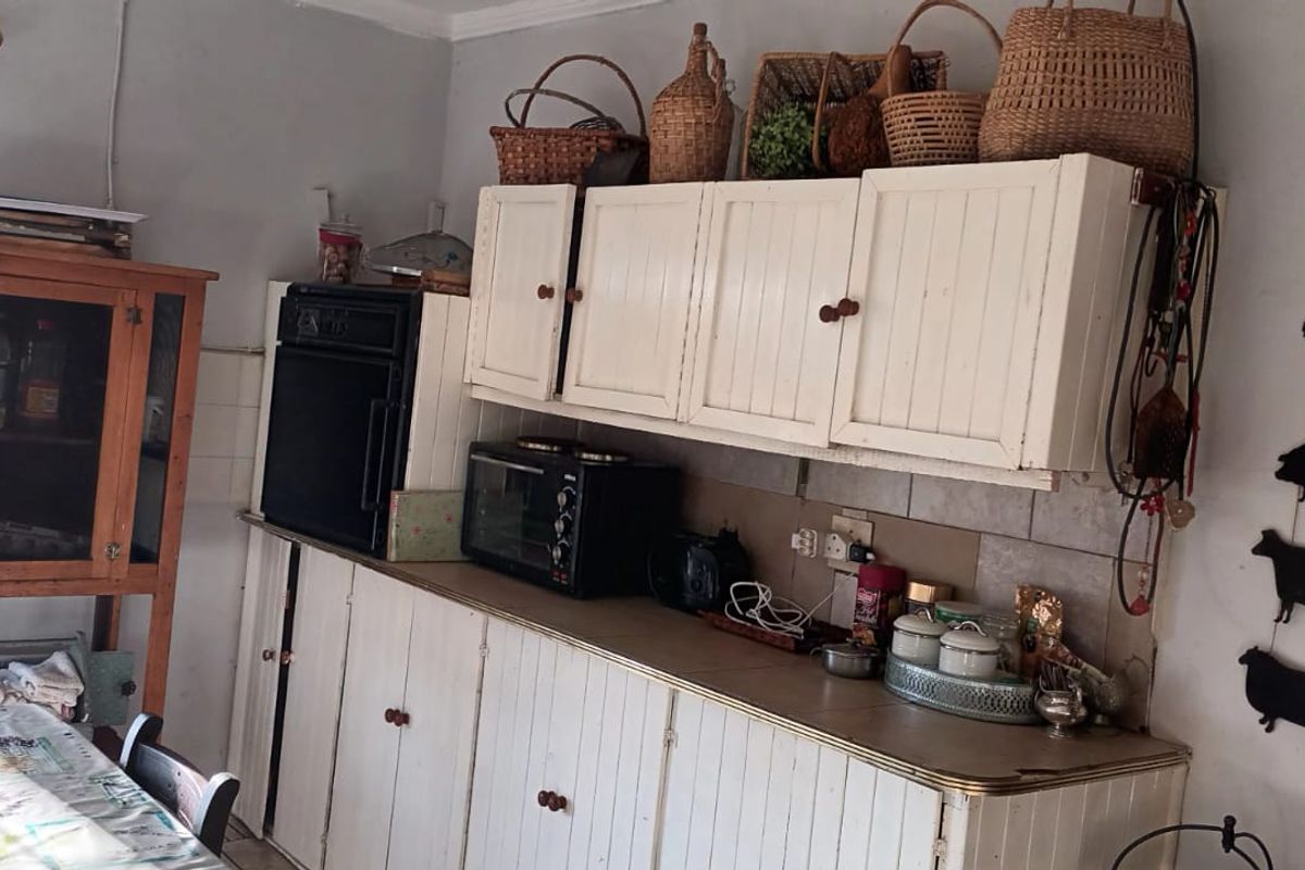 A rustic farm-style kitchen featuring white built-in cabinetry, a tiled backsplash, and a built-in oven, offering a functional space with potential for modernization.