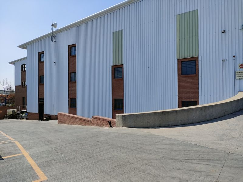 Exterior view of an industrial building featuring corrugated metal cladding, brick accents, and a concrete access ramp.