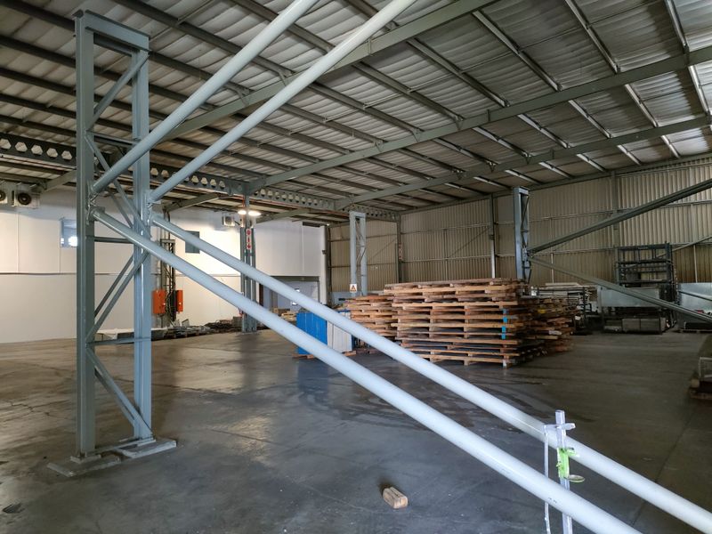 Spacious industrial warehouse unit featuring a high-clearance steel portal frame, corrugated metal roofing, and durable concrete flooring suitable for storage or manufacturing operations.