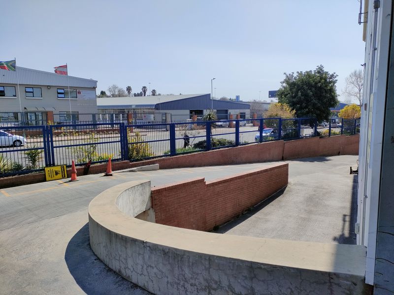 Industrial property exterior featuring a concrete access ramp, brick retaining walls, and secure perimeter fencing with paved driveway access.