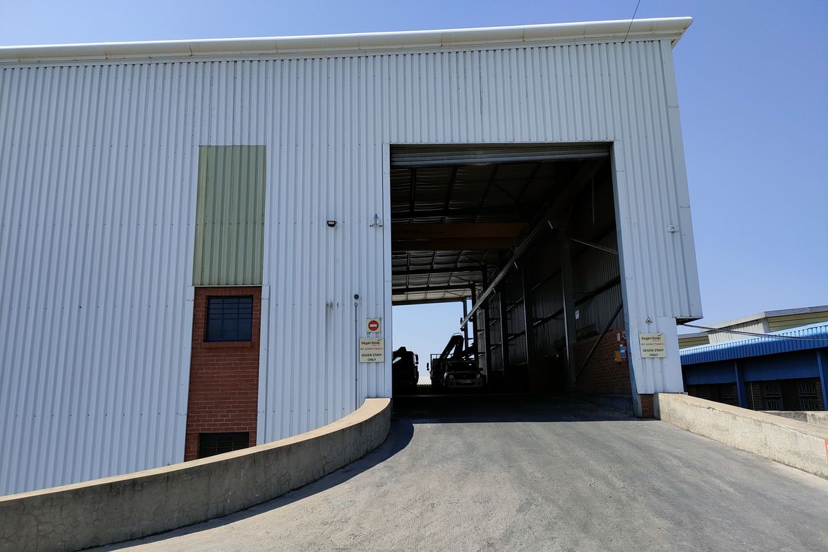 Industrial warehouse exterior featuring a large loading ramp, corrugated metal cladding, and a wide access bay for heavy vehicle entry.