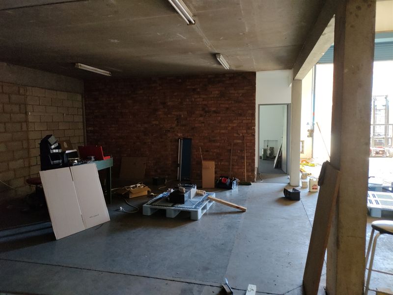 An industrial utility space featuring exposed brickwork, concrete flooring, and structural support columns, suitable for workshop or storage use.