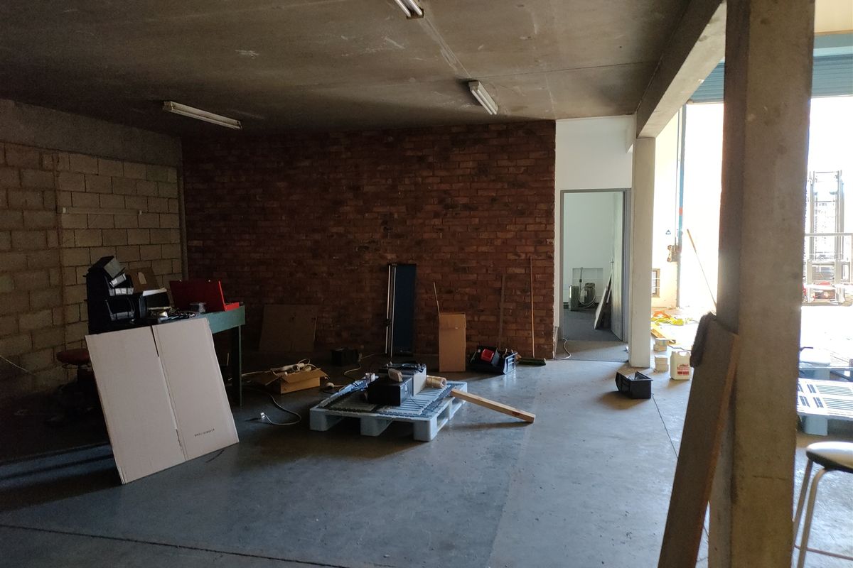 An industrial utility space featuring exposed brickwork, concrete flooring, and structural support columns, suitable for workshop or storage use.