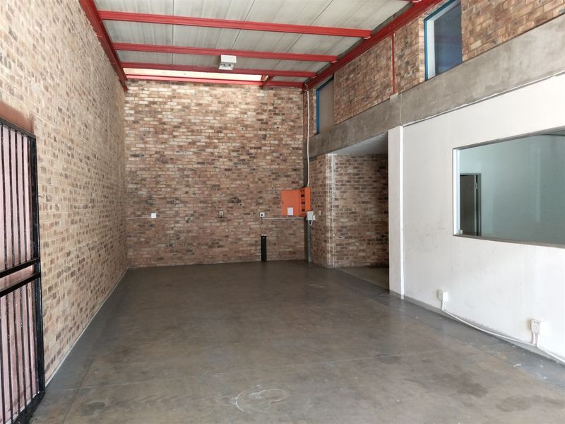 Spacious industrial utility area featuring exposed brick walls, red steel ceiling beams, concrete flooring, and an integrated electrical distribution board.