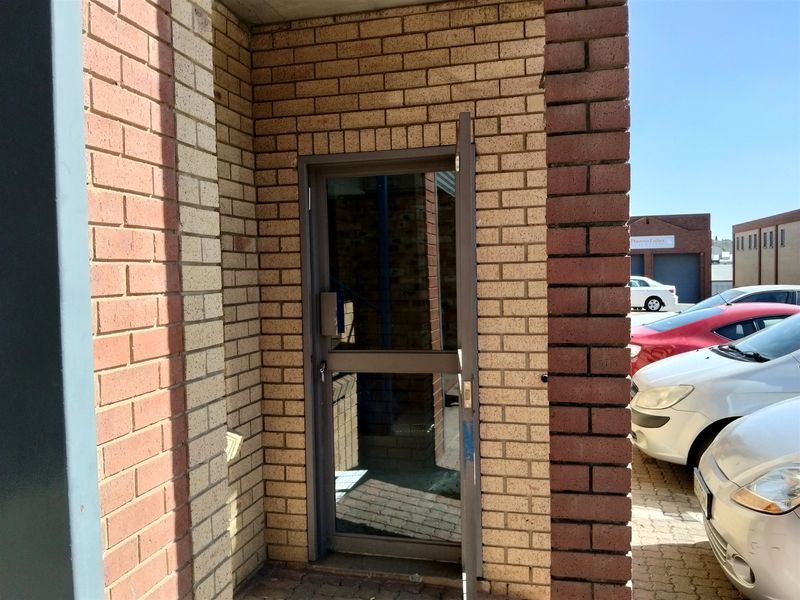 Exterior entrance featuring a brick facade and an aluminium framed glass door providing access to the industrial property.