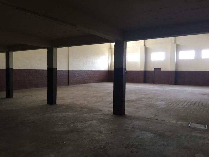 Spacious industrial utility area featuring concrete flooring, structural support columns, and high-level windows providing natural light.