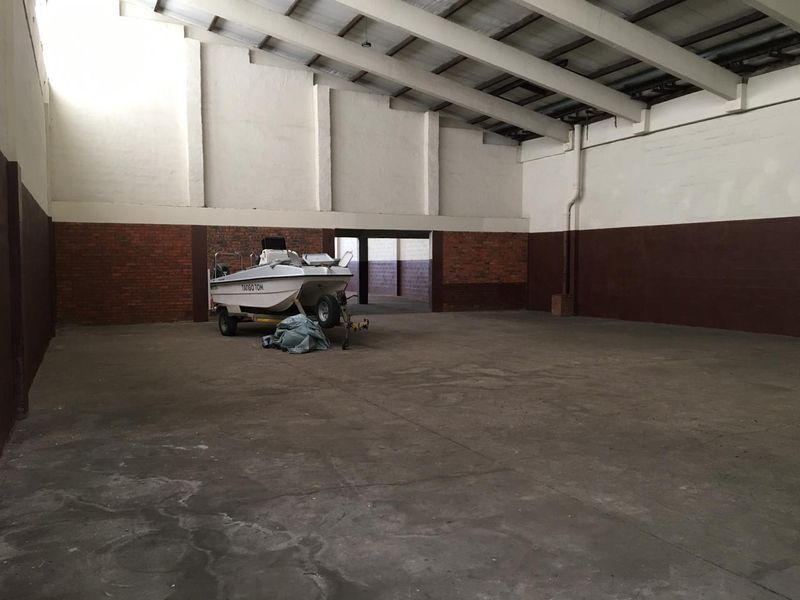 Spacious industrial utility area featuring high ceilings, exposed concrete beams, and durable concrete flooring, suitable for storage or workshop use.