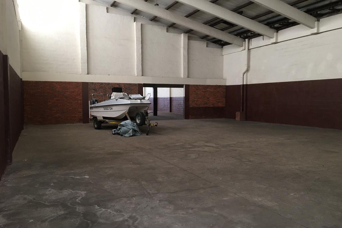 Spacious industrial utility area featuring high ceilings, exposed concrete beams, and durable concrete flooring, suitable for storage or workshop use.