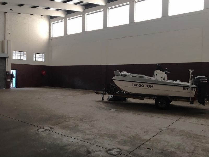 Spacious industrial utility area featuring high ceilings with exposed trusses, clerestory windows for natural light, and durable concrete flooring.