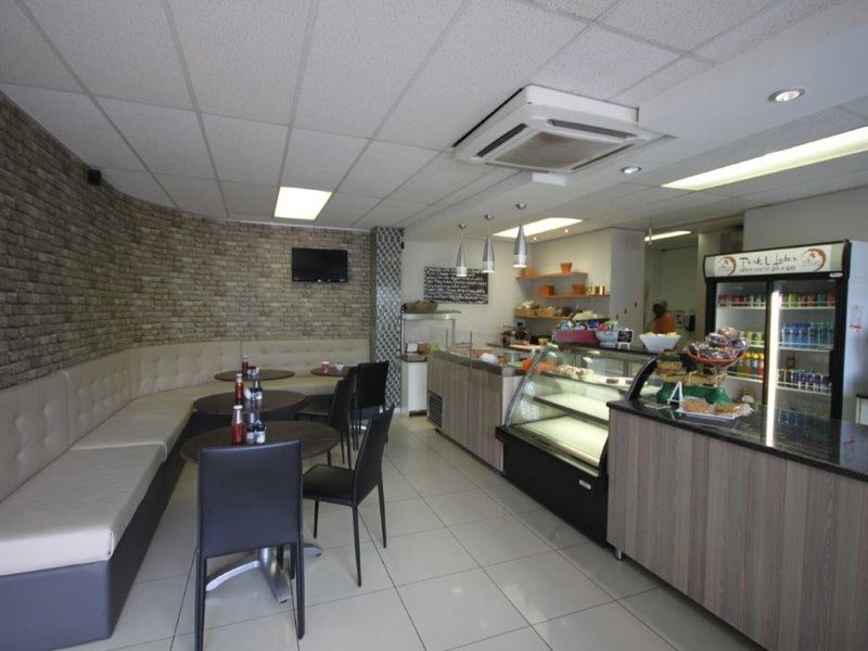 A well-maintained open-plan commercial space featuring a built-in service counter, glass display units, banquette seating, and a decorative stone-clad feature wall.