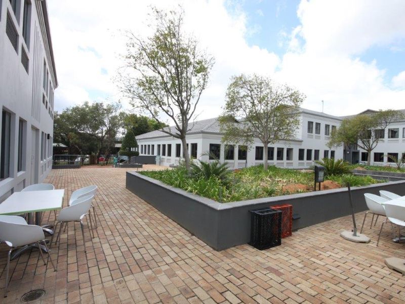 A well-maintained paved courtyard area situated between office building wings, featuring raised garden beds and professional landscaping.