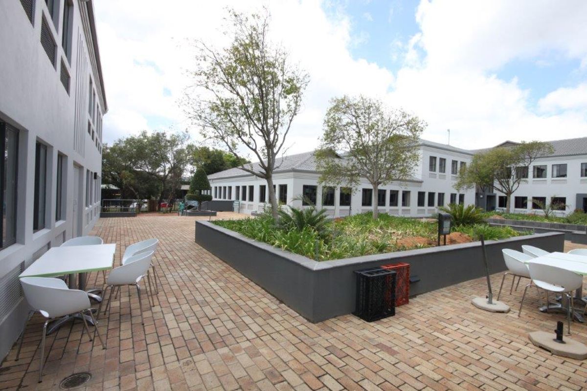 A well-maintained paved courtyard area situated between office building wings, featuring raised garden beds and professional landscaping.