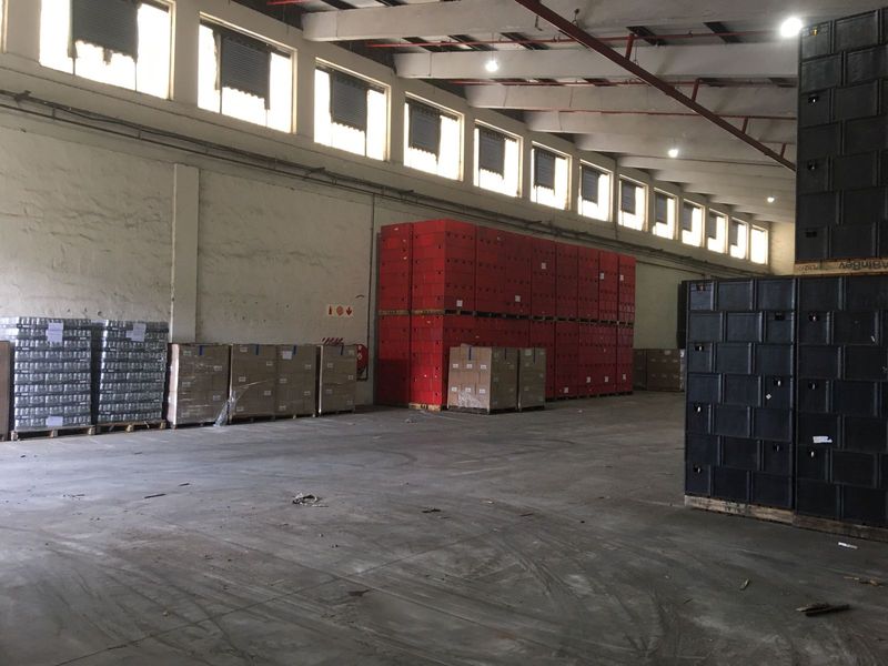 Spacious industrial warehouse area featuring high ceilings with exposed steel trusses, clerestory windows for natural light, and durable concrete flooring.