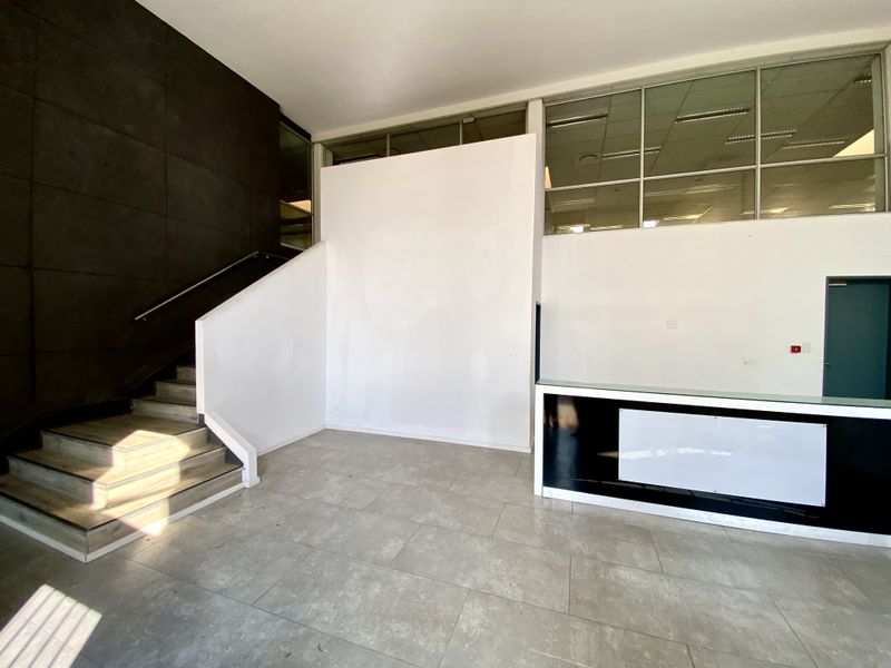 Spacious office entrance lobby featuring a built-in reception desk, tiled flooring, and a staircase leading to the upper level.