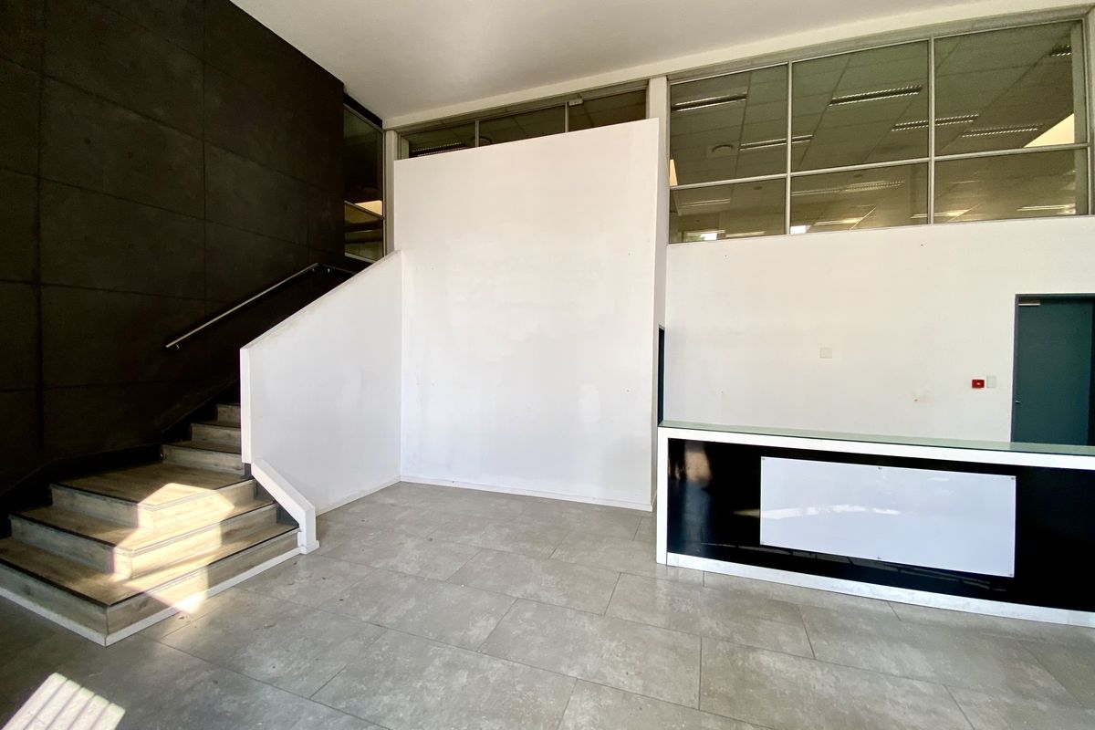 Spacious office entrance lobby featuring a built-in reception desk, tiled flooring, and a staircase leading to the upper level.