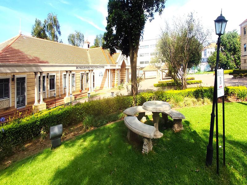 Exterior view of the Dunkeld Park Wellness Centre featuring a well-maintained garden, stone seating area, and classic architectural detailing.