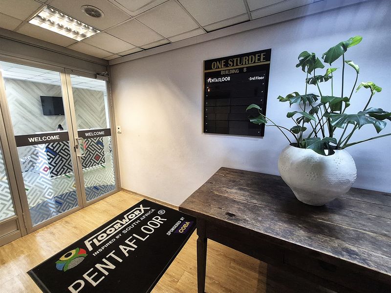 Professional office building entrance lobby featuring a glass partition door, suspended ceiling with recessed lighting, and wall-mounted directory signage.