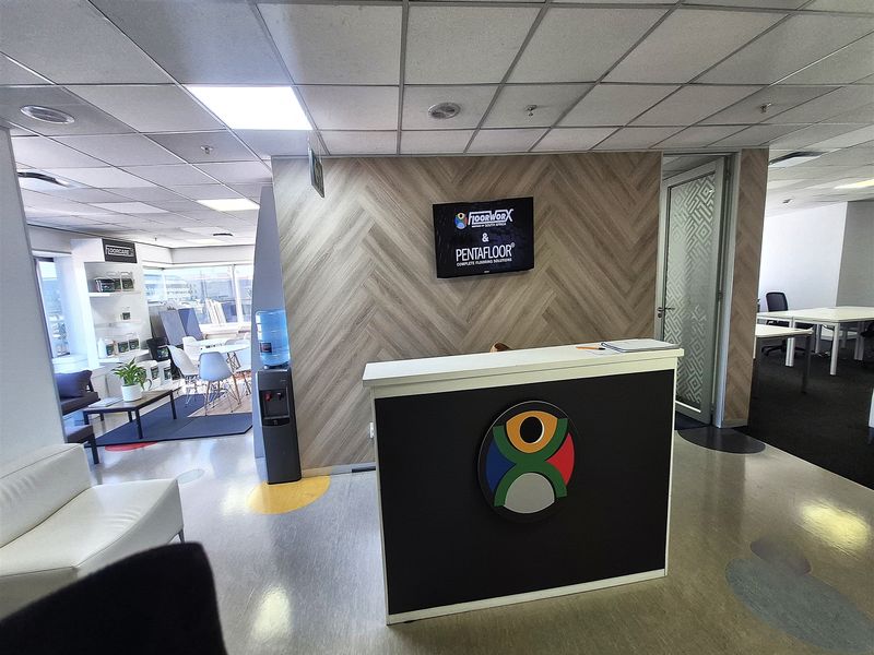 A professional office reception area featuring a modern desk, herringbone feature wall, and suspended ceiling tiles.