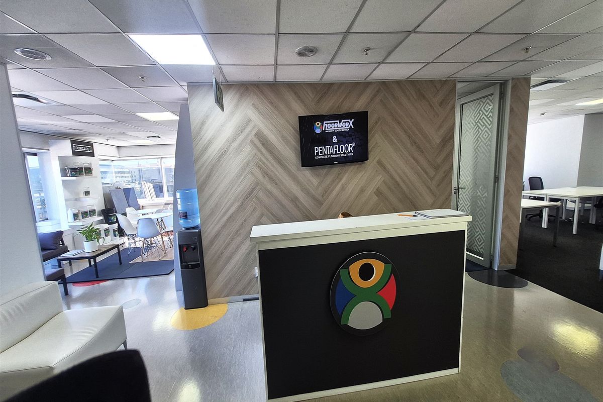 A professional office reception area featuring a modern desk, herringbone feature wall, and suspended ceiling tiles.