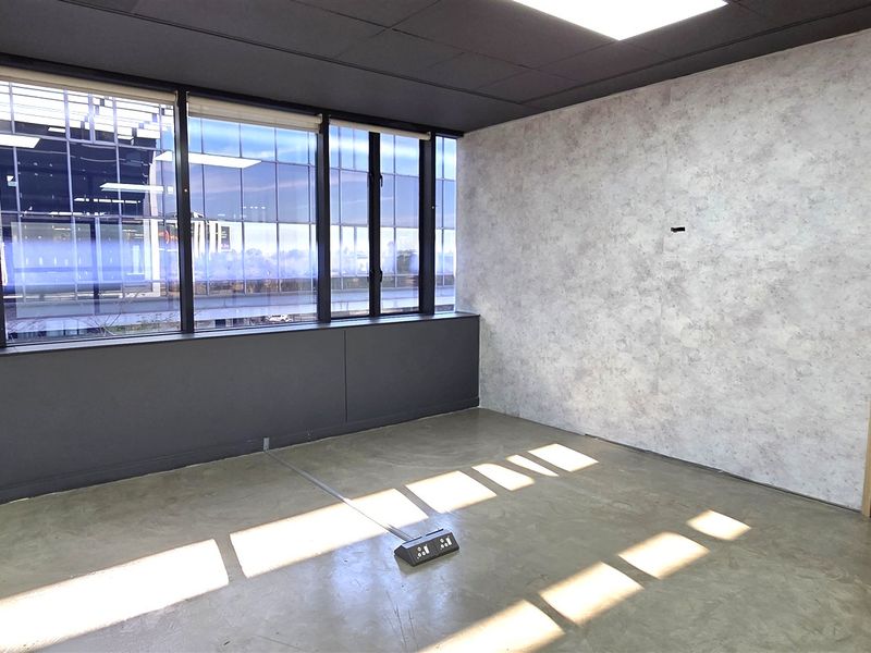 Modern office space featuring polished concrete floors, floor-to-ceiling windows, and decorative slatted wood wall paneling with integrated floor power connectivity.