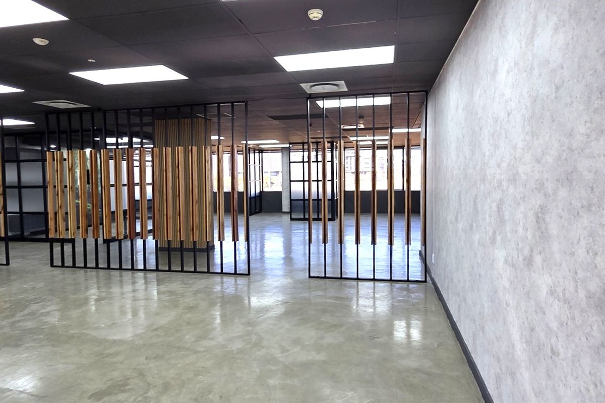 Modern open-plan office space featuring polished concrete floors, contemporary timber slat partitions, and a sleek black suspended ceiling with recessed lighting.