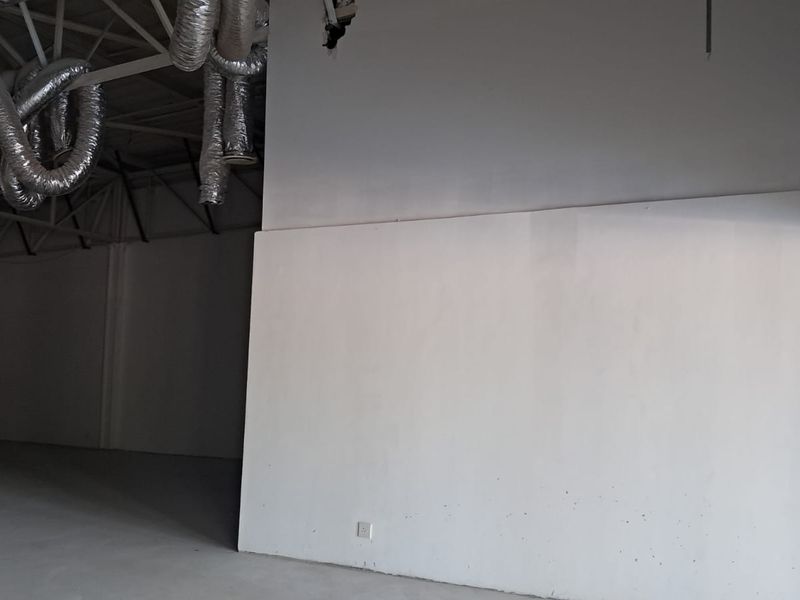 An open-plan retail space featuring exposed industrial ductwork, high ceilings, and unfinished wall sections, offering a blank canvas for custom fit-out.
