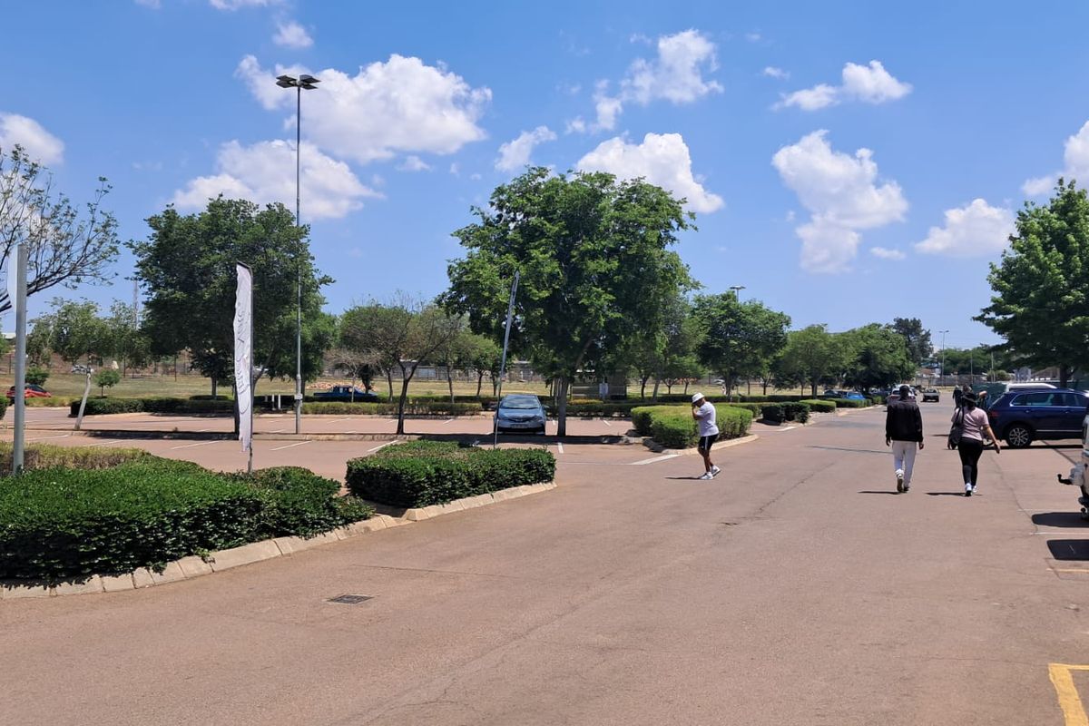 An outdoor parking area for the retail property featuring paved surfaces, landscaped garden beds, and tall lighting poles.