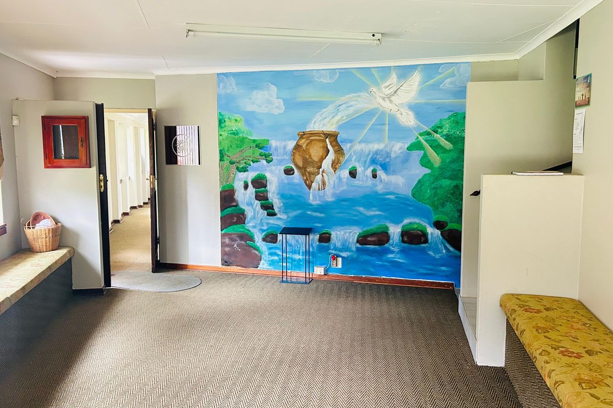 A spacious interior area featuring built-in bench seating, neutral carpet flooring, and a large decorative wall mural.