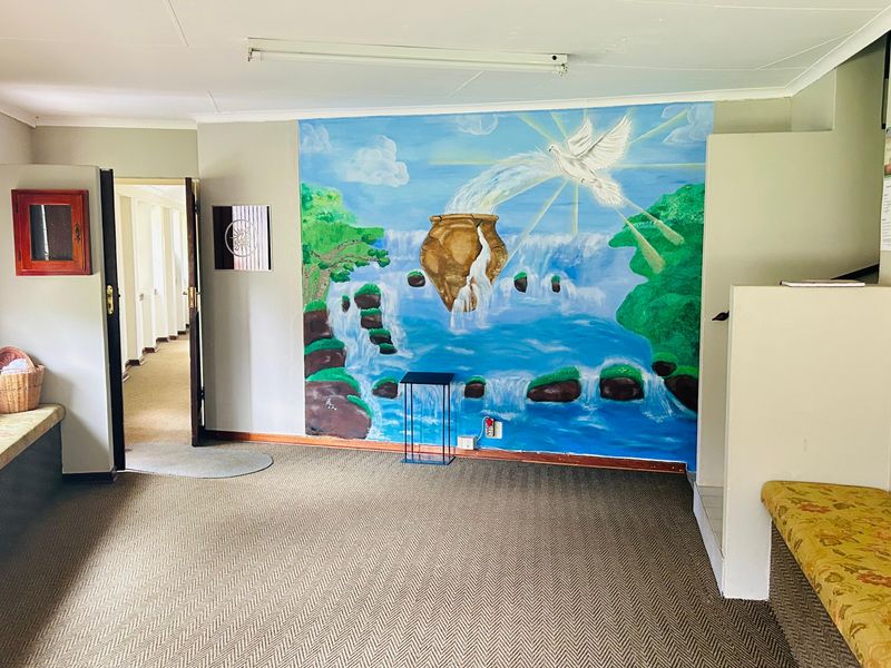 A spacious interior area featuring built-in bench seating, neutral carpet flooring, and a large decorative wall mural.