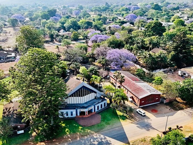 Aerial view of a commercial property complex featuring multiple buildings, mature trees, and paved access within a lush, green suburban setting.