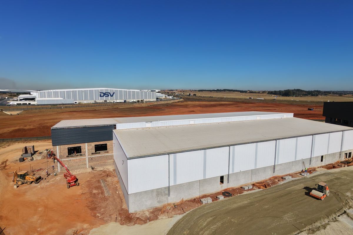 Aerial view of an industrial warehouse under construction, featuring a large metal-clad structure and surrounding site development.
