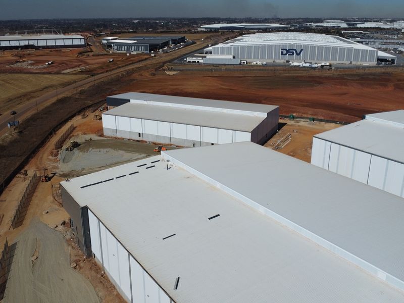 Aerial view of a large industrial park featuring multiple warehouse structures under development with surrounding access roads and open land.