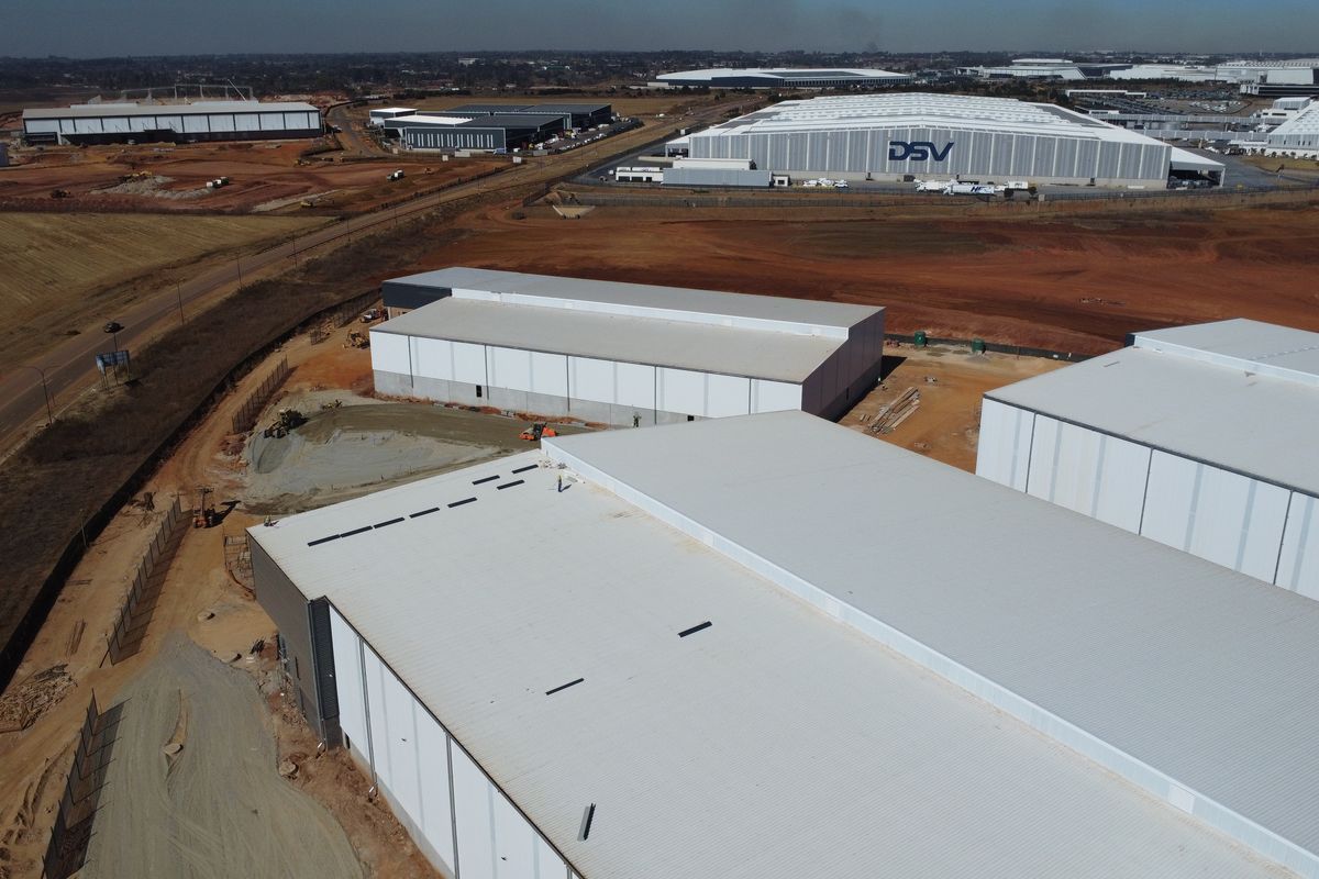 Aerial view of a large industrial park featuring multiple warehouse structures under development with surrounding access roads and open land.