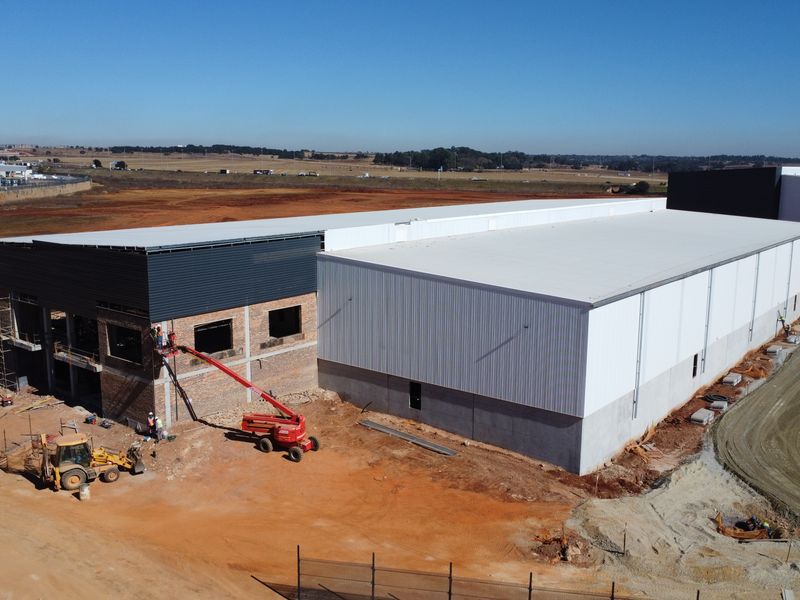 Aerial view of an industrial warehouse property under construction, featuring steel frame structure, metal cladding, and ongoing site development.