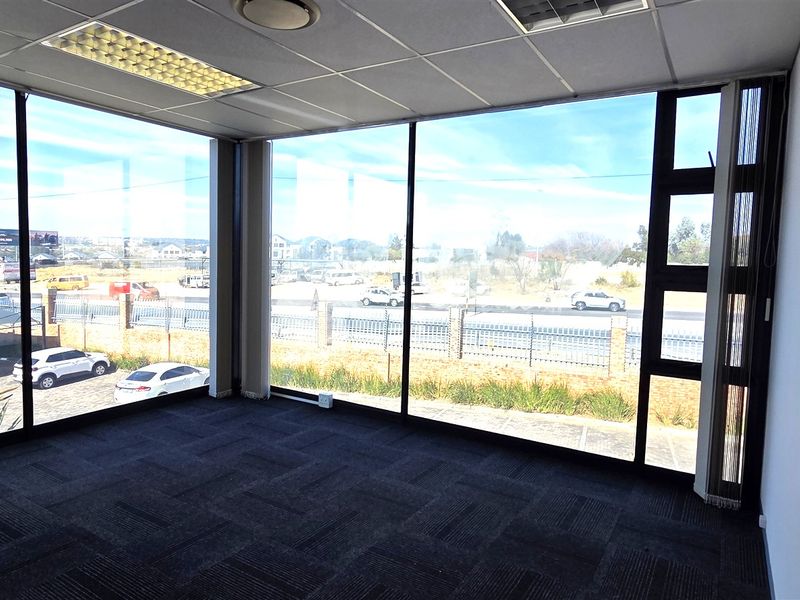 Empty office space featuring floor-to-ceiling windows, carpet tiles, and a suspended ceiling with recessed lighting, offering ample natural light.