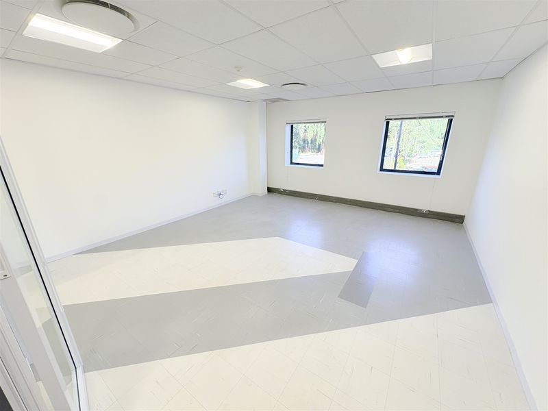 A bright, vacant office space featuring a suspended ceiling, recessed lighting, and modern patterned vinyl flooring, ready for professional fit-out.
