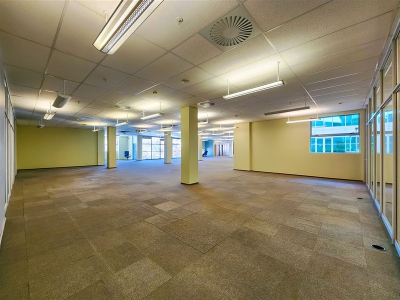 A spacious, open-plan office area featuring suspended ceilings, integrated lighting, air conditioning, and carpeted flooring, offering a versatile workspace layout.
