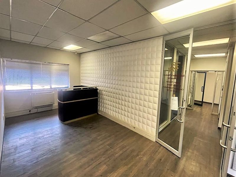 A professional office reception area featuring a glass partition door, suspended ceiling, and modern wall paneling, providing a clean and functional workspace.