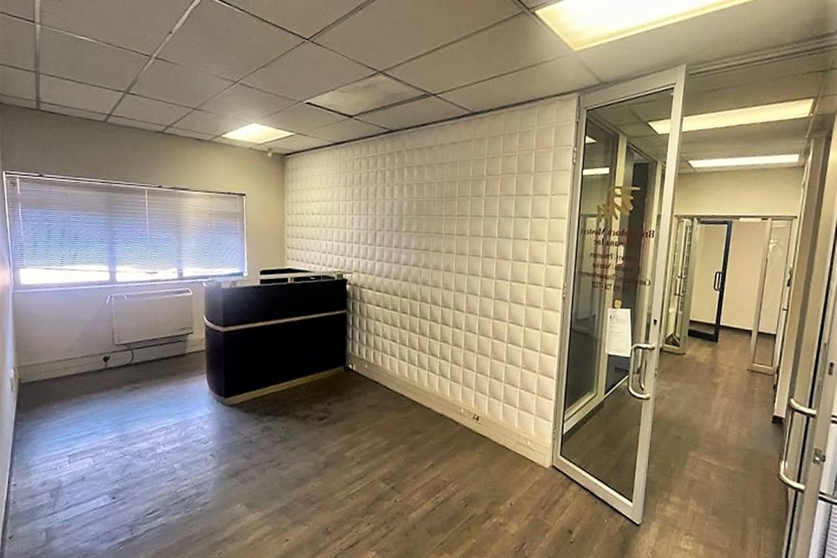 A professional office reception area featuring a glass partition door, suspended ceiling, and modern wall paneling, providing a clean and functional workspace.