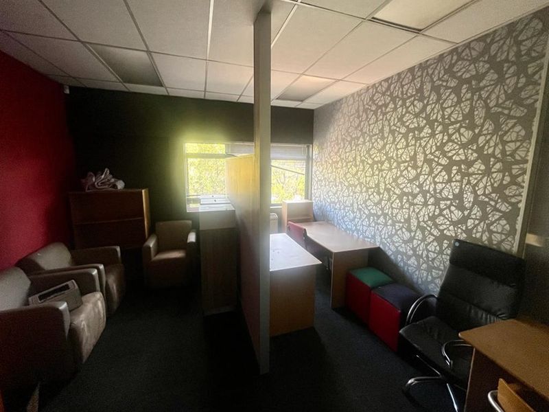 A partitioned office space featuring a suspended ceiling, carpeted flooring, and a mix of dark and patterned wall finishes.