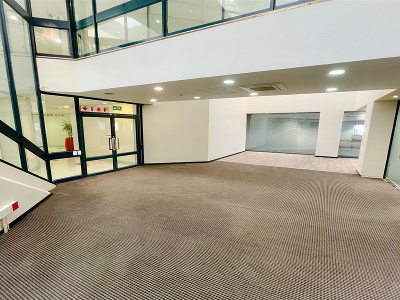 Spacious open-plan office area featuring modern glass partitioning, recessed lighting, and neutral carpeting, providing a versatile and professional workspace environment.
