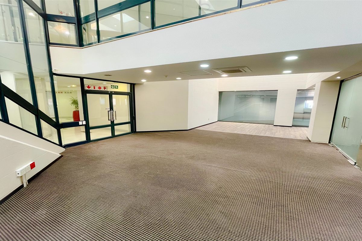 Spacious open-plan office area featuring modern glass partitioning, recessed lighting, and neutral carpeting, providing a versatile and professional workspace environment.