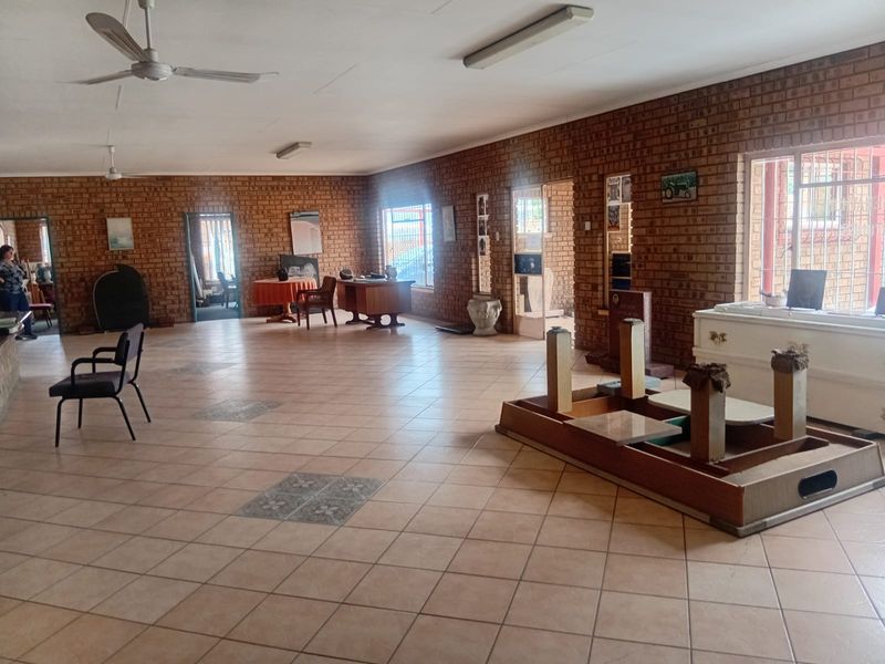 Spacious open-plan industrial area featuring exposed brick walls, ceramic tile flooring, and functional ceiling lighting, suitable for various commercial or office applications.