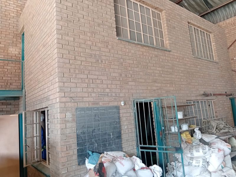 Industrial utility space featuring exposed brick walls, a mezzanine level, and secure steel access points, suitable for workshop or storage use.