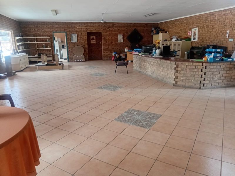 Spacious industrial office area featuring exposed brick walls, ceramic tiled flooring, and a built-in brick reception counter.