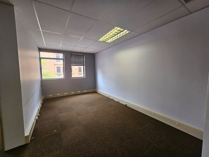 Empty office space featuring carpeted flooring, suspended ceiling with recessed lighting, and perimeter trunking for electrical connectivity.