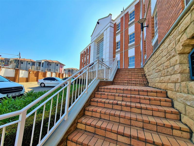 Exterior view of the office building entrance featuring a brick staircase with metal railings and stone cladding accents.