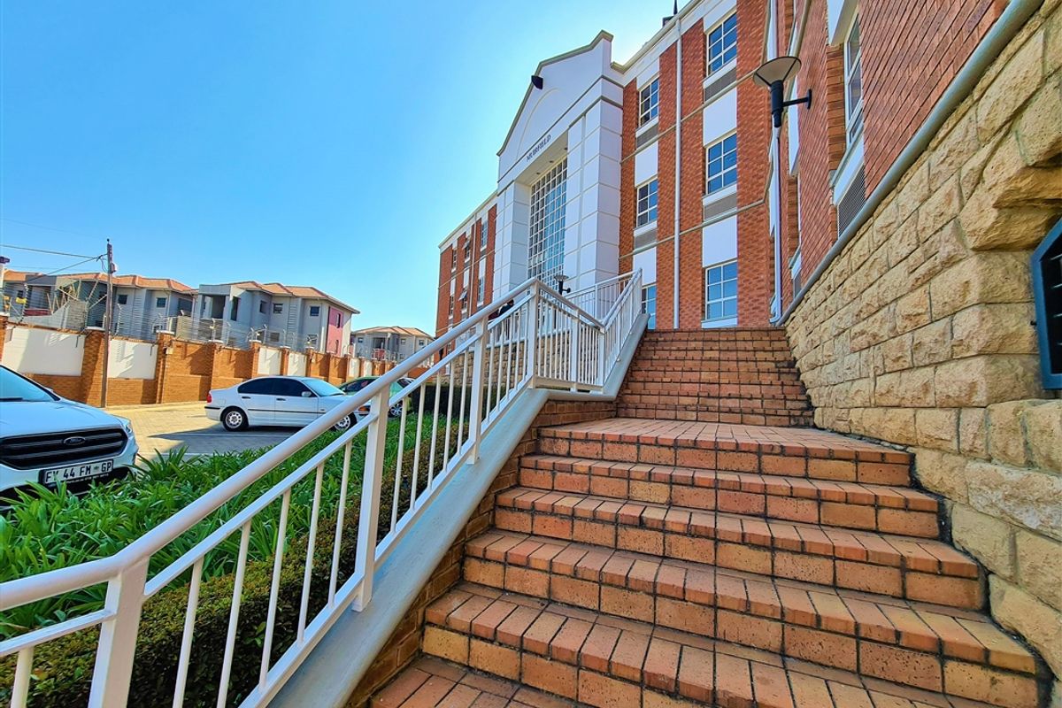 Exterior view of the office building entrance featuring a brick staircase with metal railings and stone cladding accents.