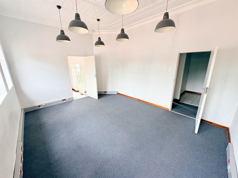 A bright, empty office space featuring decorative ceiling detailing, modern pendant lighting, and perimeter electrical trunking for connectivity.