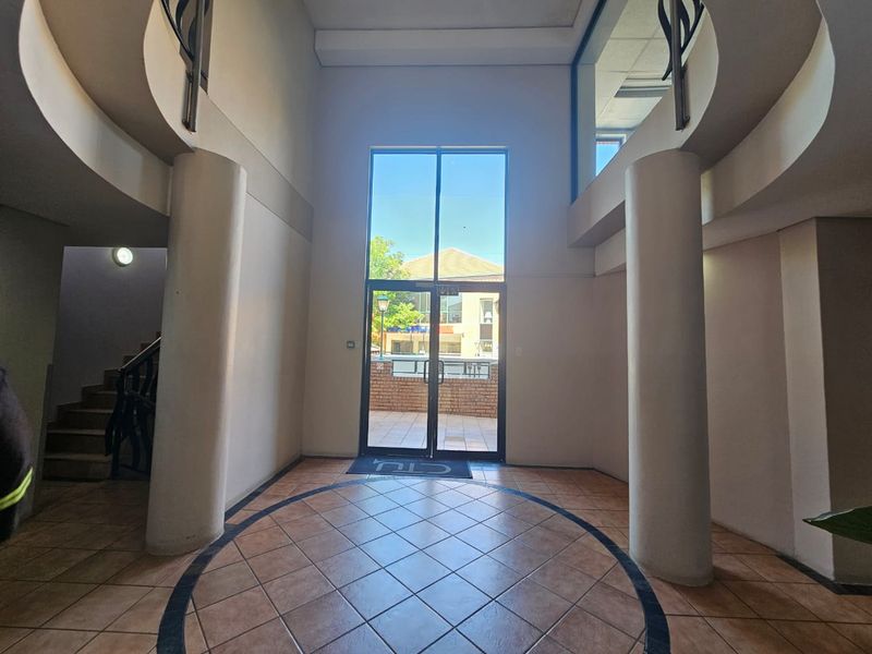 Spacious double-volume entrance foyer featuring tiled flooring, structural columns, and a grand staircase leading to the upper level.
